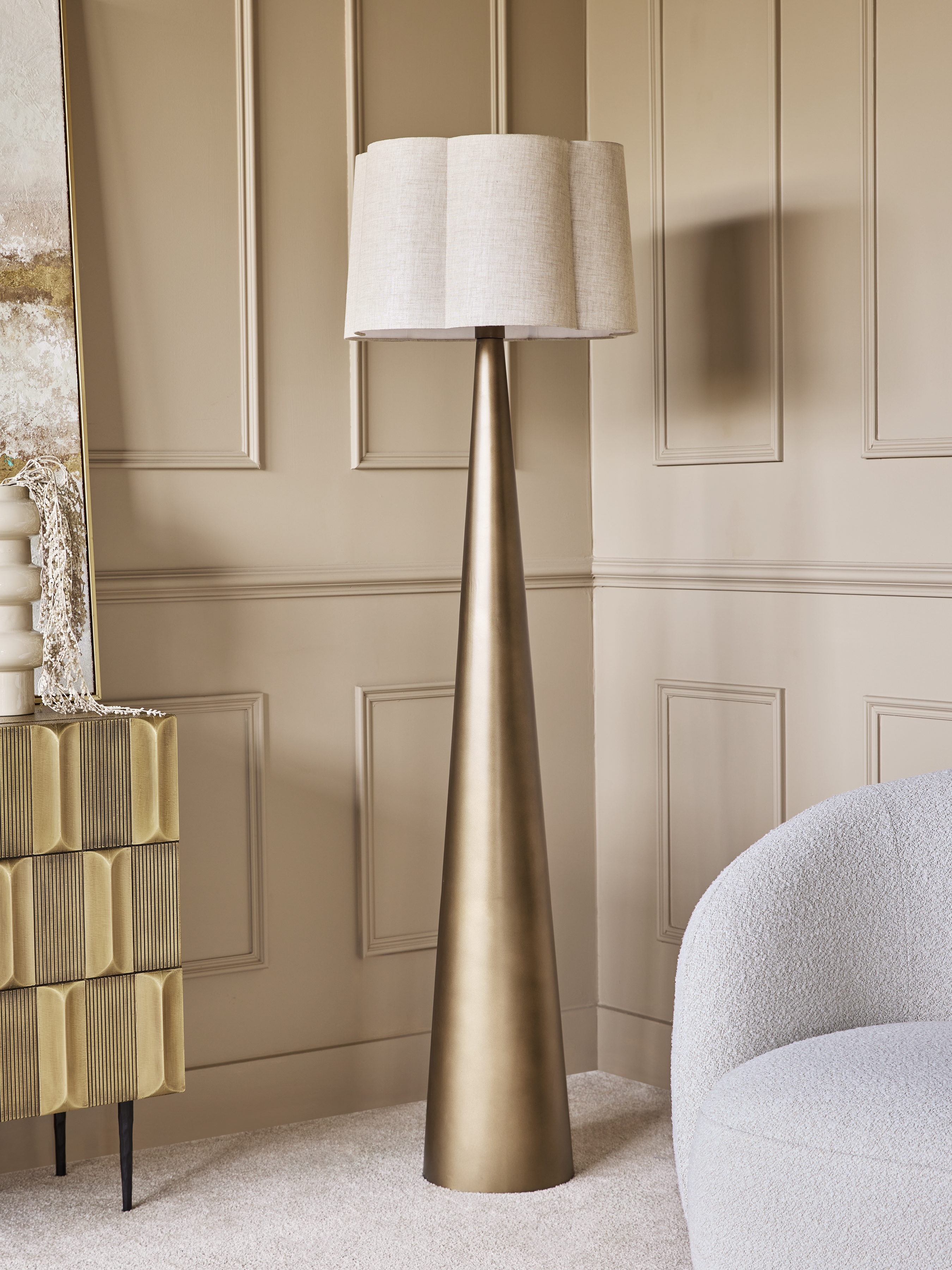 Contemporary brushed brass floor lamp with a neutral linen shade in a living room setting.
